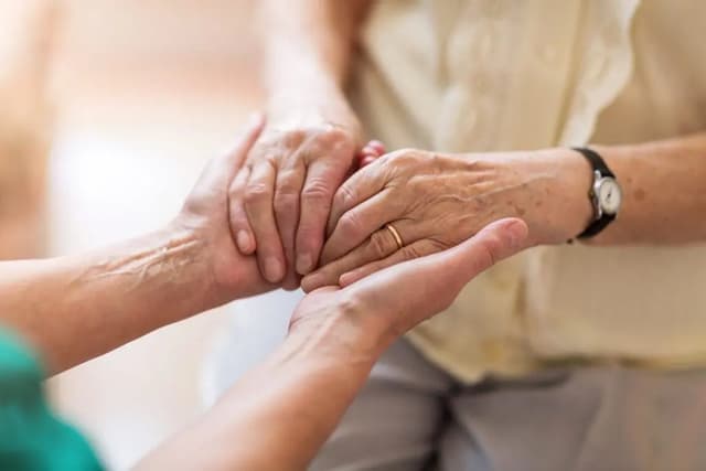Two pairs of hands gently clasped together