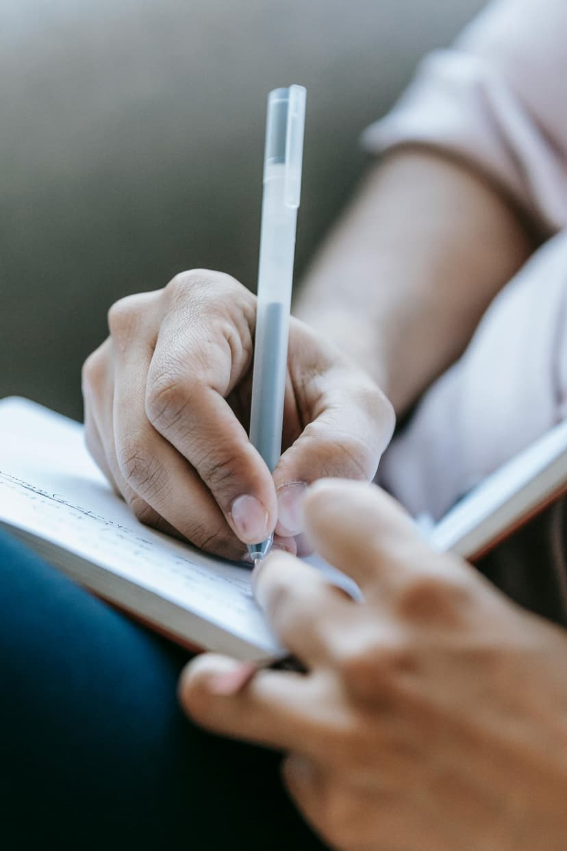 Person writing in notebook with pen