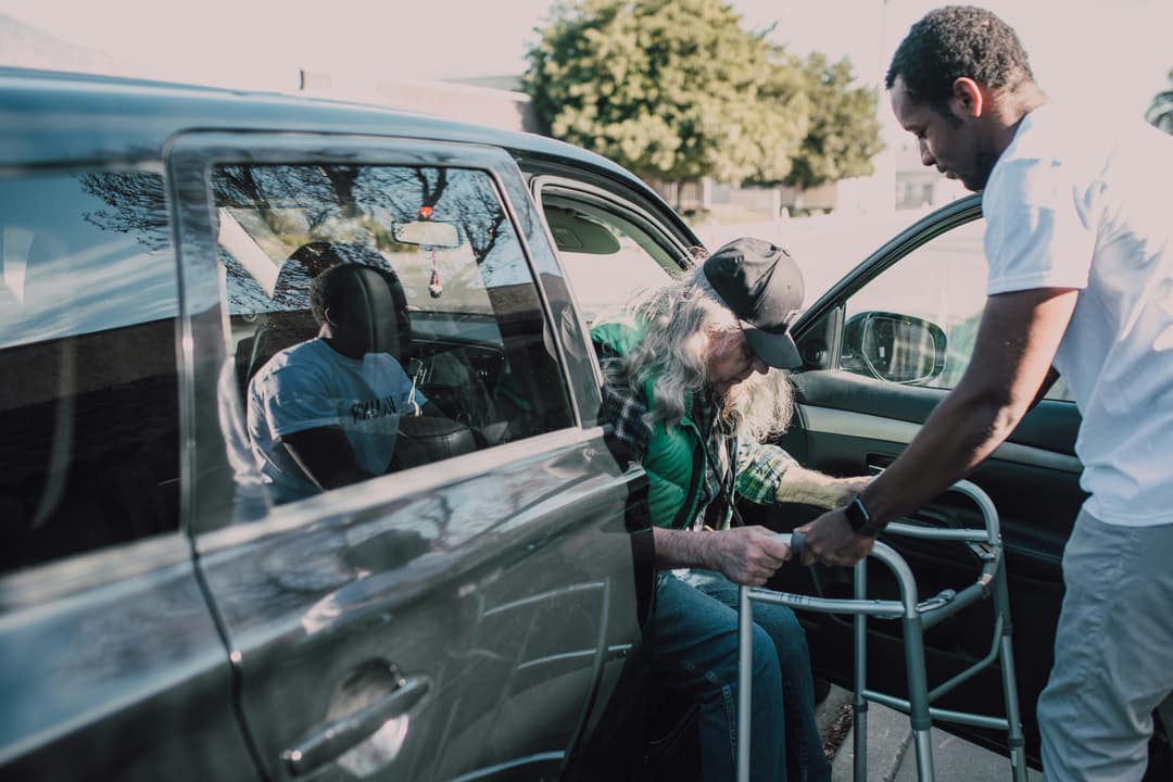Man assisting elderly person with walker